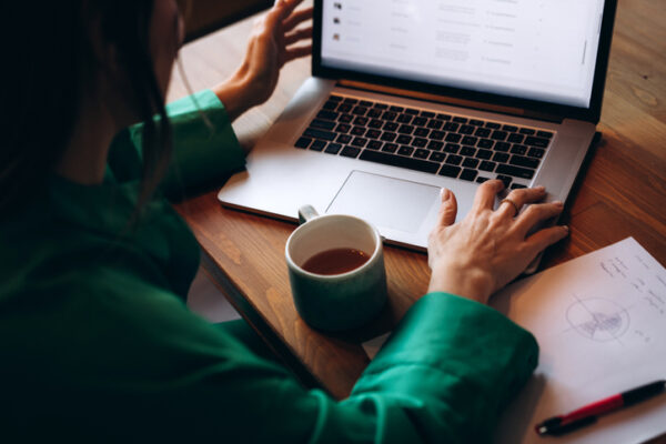 An unrecognizable woman working on her laptop in the office
