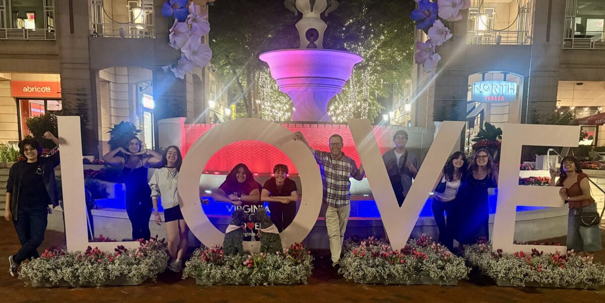 Nine college students flank the LOVE sculpture in the Reston Town Center, Virginia, accompanied by their professor in the middle