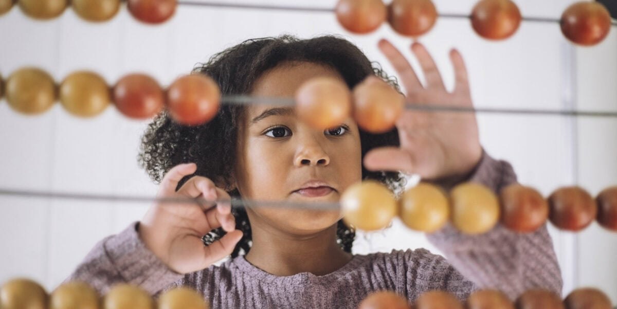 Girl learning to count using abacus in classroom at kindergarten