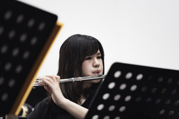 Student playing a flute behind music stand