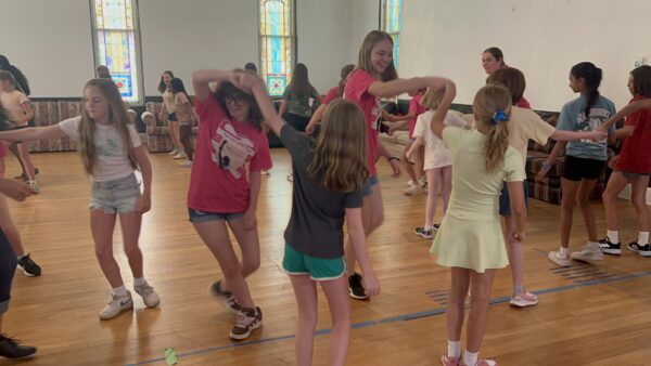 smiling girls dancing and wearing pink Confidence Camp branded tshirts