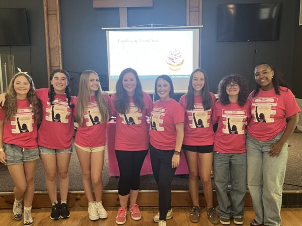 group of young girls and counselors wearing pink branded tshirts pose for photo