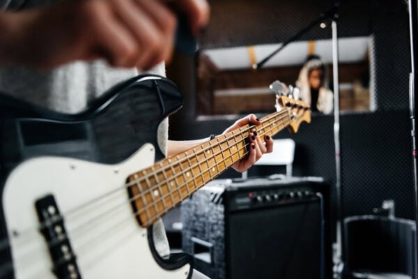 Close-up shot of a musician's hand playing a guitar in a record studio
