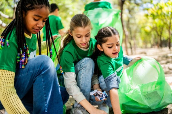 students in green t-shirts helping in outdoor cleanup