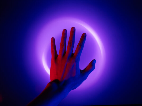 Upheld hand on purple lighting on dark background