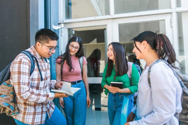 Latine university students chatting and sharing, outside the classroom building.