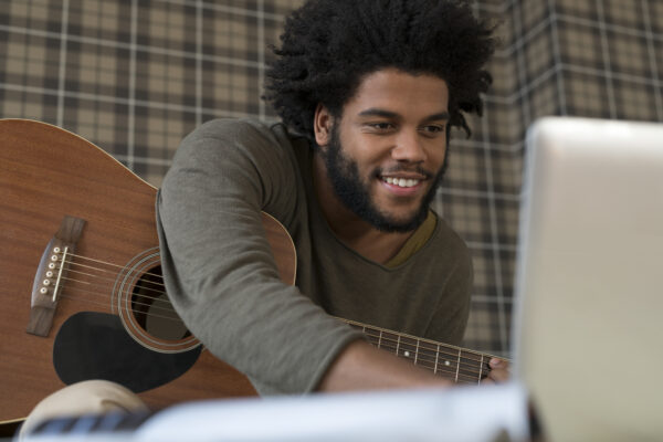 Man with guitar looking at laptop