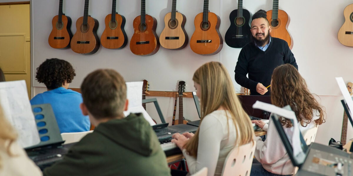 Newer teacher with keyboard and guitar students in class