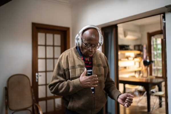 Senior man listening to music at home wearing headphones