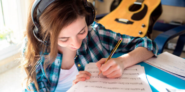 smiling girl writing music for guitar