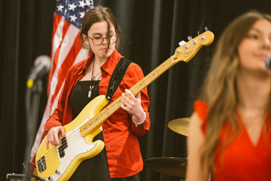 student guitarist performing on stage with commercial music band